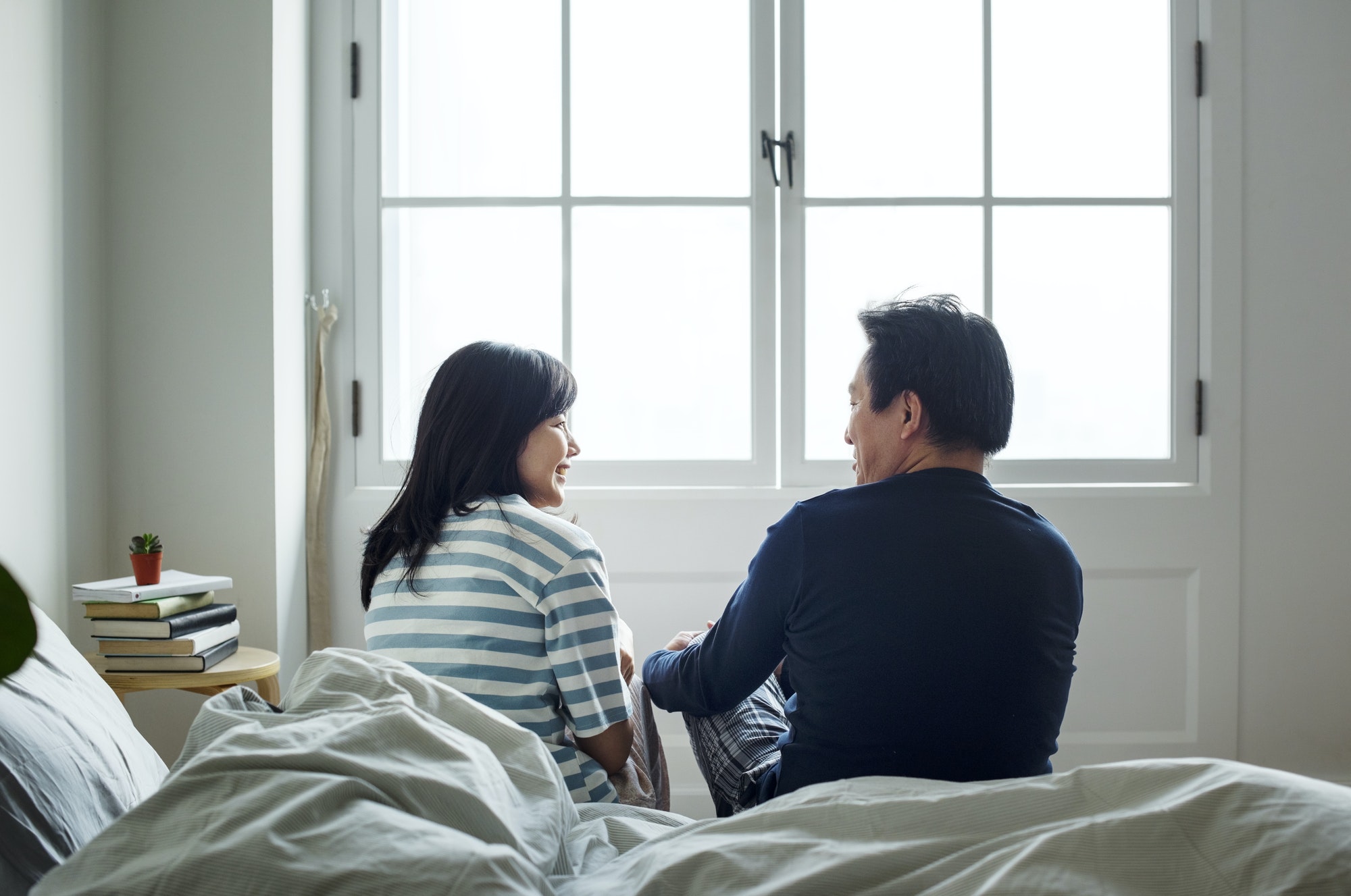 Asian couple talking together in bed