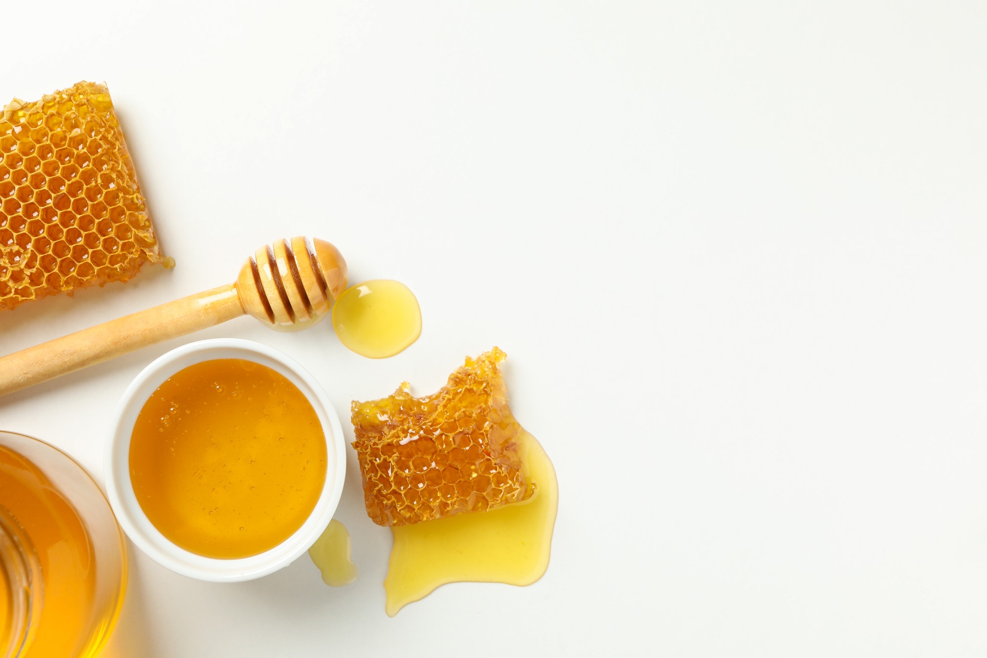 Bowl with honey, dipper and honeycombs on white background