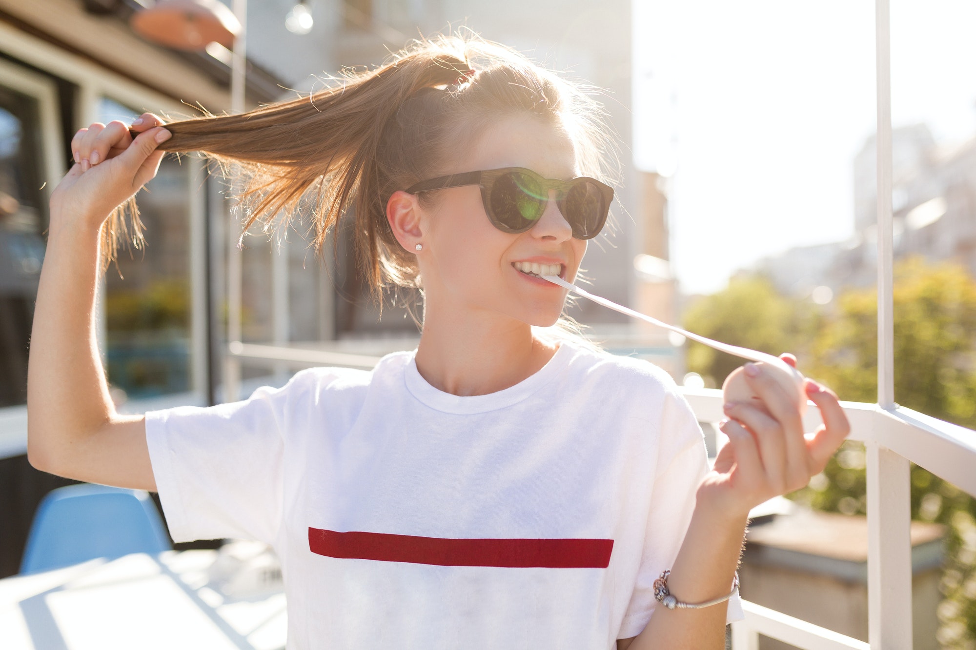 Funny excited joyful girl with tail dressed white shirt and sunglasses pulls the tail