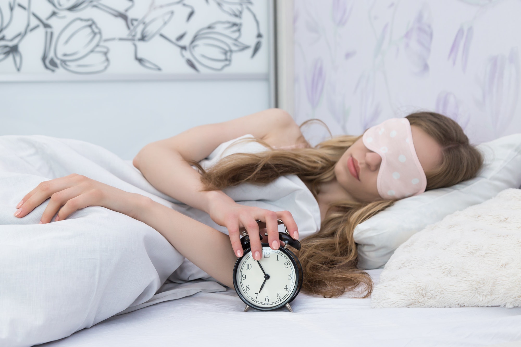 sleeping girl of European appearance with alarm clocks in her hands